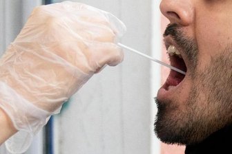 Ein Patient lässt vor einer Arztpraxis einen Abstrich machen.
