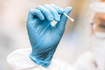 Eine medizinische Mitarbeiterin hält einen Tupfer für einen Abstrich für einen Corona-Test in der Hand.