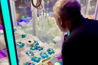Coronavirus: Britischer Ferienpark-Betreiber befüllt Spielautomaten mit Klopapier - Ein Mann spielt an einem Spielautomaten, in dem mehrere Flaschen Desinfektionsmittel liegen. Der Betreiber eines britischen Ferienparks hat als Reaktion auf Hamsterkäufe wegen der Covid-19-Epidemie seine Spielautomaten mit Toilettenpapier und Desinfektionsmittel befüllt. Wo es sonst gilt, mit einem Greifarm Teddybären und andere Stofftiere aus dem Automaten zu angeln, sind jetzt die weißen Rollen und Flaschen mit Desinfektionsgel zu gewinnen. 