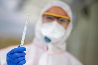 Ein Mitarbeiter hält in einem Abstrichzentrum einen Coronatest-Abstrich in der Hand.