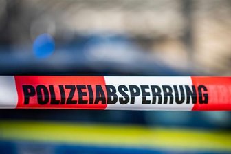 Ein Absperrband mit der Aufschrift "Polizeiabsperrung" ist vor einem Polizeiwagen aufgespannt.