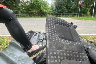 Crimmitschau: Müllärger im Ortsteil Frankenhausen nimmt überraschende Wende - Eine Spaziergängerin stochert im Unrat an der Uferstraße in Frankenhausen nahe der Autobahnbrücke herum. An dieser Stelle sollen die Anlieger des Paradiesweges ihren Sperrmüll abstellen. Im Hintergrund ist der Zugang zur Fußgängerbrücke zu sehen, die zum Paradiesweg führt.