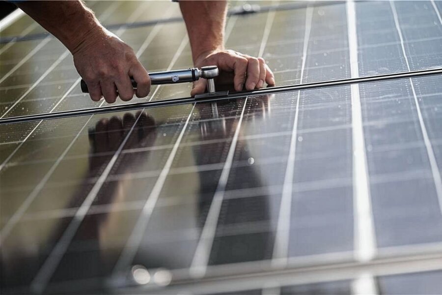 Crimmitschau senkt eigenen Energieverbrauch drastisch - Mitarbeiter einer Firma montieren Fotovoltaikmodule auf dem Dach eines Hauses (Symbolbild). 