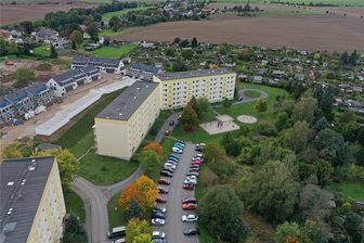 Crimmitschau: Viele Westberg-Bewohner sind von Reihenhäuschen nicht begeistert - Auf den Balkonseiten der Plattenbauen an der Bebelstraße werden weitere Reihenhäuser (im Foto links) gebaut. Anwohner fürchten, dass der Grünstreifen an den Seiten mit den Hauseingängen (rechts) bald auch noch verschwindet.