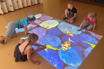 Crimmitschau: Was es mit dem „Magischen Teppich“ in der Kita „Mischka“ auf sich hat - Der „Magische Teppich“ in DRK-Kita „Mischka“ in Crimmitschau ist bei den Mädchen und Jungen beliebt. Hier spielen Simon, Ella, Finn-Luka und Julia (von links) mit den Fischen im Teich, die sich nach jeder Berührung bewegen.
