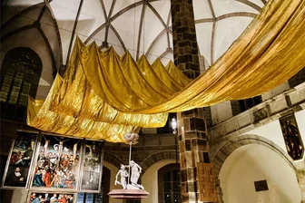 Da staunt selbst der Pfarrer: Goldne Altar-Kunst im Schneeberger Bergmannsdom überrascht - Der Kunstweg Purple Path der Europäischen Kulturhauptstadt Chemnitz 2025 hat eine temporäre Station in Schneeberg: Eine goldene Wolke bereichert die Wolfgangskirche in Schneeberg als Kunstwerk bis Ostersonntag. Sie erinnert an eine Tradition der Fastenzeit. Geschaffen hat sie Textilkünstler Ulrich Reimkasten aus Organzagewebe.