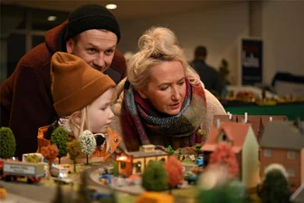 Damit auch künftig noch Züge in Rochlitz rollen: Modellbahner wollen Nachwuchs begeistern - Traditionell zeigt der Modelleisenbahnverein „Goldenes Tal Biesern“ zum Rochlitzer Weihnachtsmarkt Modellbahnen im VW-Autohaus Lohs. Auch Tim Stölzel und Madeleine Schilde mit Tochter Milla sahen sich die Ausstellung an.