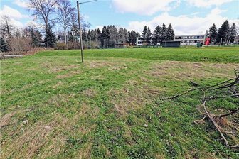 Damoklesschwert über Wohngebiet: Großhartmannsdorf muss für Regenrückhaltebecken tief in die Kasse greifen - Auf der Fläche im Vordergrund soll das Regenrückhaltebecken gebaut werden. Im Hintergrund die Kindertagesstätte Großhartmannsdorf. 