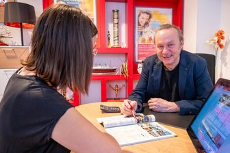 „Dann kam Corona, und die Welt stand still“: Wie ein Reisebüro im Erzgebirge nach der Pandemie wieder durchstartet - Touristikfachwirt Mirko Müller im Beratungsgespräch mit einer Kundin. Das Dertour-Reisebüro in Olbernhau blickt auf 65 Jahre Geschichte zurück.
