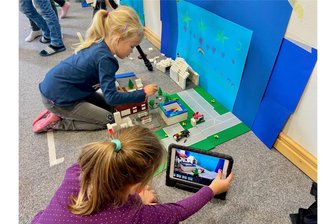 Das etwas andere Ferienprojekt: Wie Erzgebirgsgeschichte, Lego und Tablets kleine Regisseure fordern - Magdalena (hinten) und Louise arbeiten zusammen an ihrem Lego-Stop-Motion-Film anhand eines Tablets vor ihrer selbstgemalten Kulisse in den Räumlichkeiten der Stadtbibliothek Oelsnitz. Beide sind sechs Jahre alt.