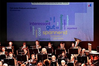 Das Freiberger Theater holt mit einem besonderen Jugendkonzert Richard Wagner in die Moderne - Beim Schülerkonzert „Die Herrn der Ringe“ mit der Mittelsächsischen Philharmonie in Freiberg ploppen auf einer Projektionsfläche hinter dem Orchester Schlagwörter auf – gepostet vom Publikum auf die Frage nach dem ersten Eindruck vom Konzert.