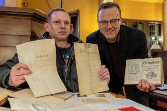 Das gibts selten: Friedhof gehört dem Ort - Der Grünbacher Ortschronist Jan Hartmann Ortschronist (links) und Pfarrer Jörg Grundmann mit einem alten Gesangsbuch und Kaufurkunden zum Friedhof. 