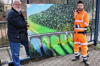 Das Hetzdorfer Viadukt im Buswartehaus in Falkenau - Martin Müller. der stellvertretende Vorsitzende des Heimatvereins Falkenau (l.), freute sich, dass ein Team des Bauhofes Flöha um Benjamin Heilmann (r.) die Montage des gemalten Bildes an der Bushaltestelle in Falkenau übernahm. 