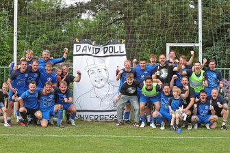 „Das ist für David“: Fußballer des TV Oberfrohna jubeln über Meistertitel und Aufstieg - Die Mannschaft des TV Oberfrohna feierte den Meistertitel in der Westsachsenliga vor der Zaunfahne mit dem Konterfei des verstorbenen Mannschaftsleiters David Doll.