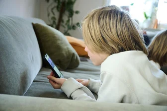 Das Smartphone im Kinderzimmer: Infoabend zur Medienerziehung in Plauen - Ein Junge liegt auf einem Sofa und guckt auf sein Smartphone.