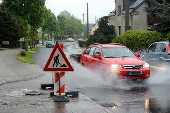 Das Straßenfest fällt ins Wasser - Wie hier in Neustadt, so wurden an mehreren Orten der Region die Gullydeckel durch den Wasserdruck aus Gehwegen und Straßen gedrückt. Autos verwandelten sich stellenweise in Amphibienfahrzeuge.