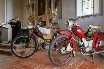 DDR-Mopeds in Kirche: Simson-Gemeinde feiert Zusammenhalt - Pfarrerin Susanne Noack spricht in der Kirche - neben ihr die Kult-Mopeds.