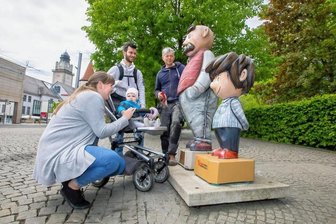 Demolierte Vater-und-Sohn-Figuren in Plauens Innenstadt: Holzbildhauer schafft Ersatz - Holzbildhauer Hartmut Rademann (rechts) vorm Theatercafé im Gespräch mit Familie Matthes - Saskia, Benjamin und der einjährigen Tochter Pauline. Den "Sohn" hat der Handwerkskünstler hier komplett ersetzt.
