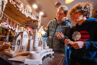 Der heimeligste Weihnachtsort im Vogtland: Hier trifft Holzkunst auf Hexenküche - Deko geht immer, sagt Elisabeth Blenz. Mit Sohn Ludwig schaut sie sich in der Holzwerkstatt von Steffen Laudel um. Viele atmosphärische Orte bot der Markt in der Elsteraue.
