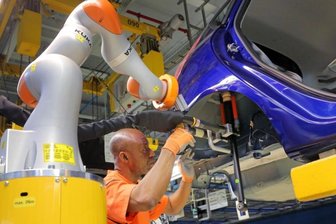 Der Mensch ist in der digitalen Welt ein Unsicherheitsfaktor - Zusammenarbeit von Mensch und Maschine in der Ford-Fertigung in Köln: Ausgestattet mit Schrauben und Stoßdämpfer fährt der Leichtbauroboter automatisch in Richtung des Radhauses der Fahrzeug-Karosserie. Dort kontrolliert der Mitarbeiter noch einmal die Position und gibt das Signal zum Schrauben.