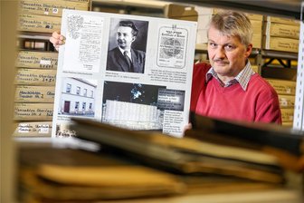 Der Oskar Schindler des Vogtlandes - vor 80 Jahren starb Alfred Roßner - Ralph Ide steht mit einem Ausstellungsposter zu Alfred Roßner im Falkensteiner Stadtarchiv. Roßner rettete als treuhänderischer Leiter einer Textilfabrik in Polen während der Nazizeit mehreren Juden das Leben.