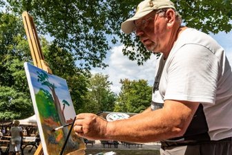 Der Sommer im Wettinhain: Schlagerdebüt, Malen, Basteln - Der Burgstädter Hobbymaler Uwe Kühnert hat beim ersten Kreativnachmittag für Jedermann im Wettinhain mit Acrylfarben auf Leinwand eine 100 Jahre alte Eiche gemalt, die neben der Freilichtbühne steht. Seine Werke stellte der 63-Jährige bereits im Taurasteinturm und im Lunzenauer Rathaus aus. 