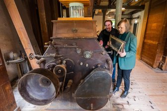 Deutscher Mühlentag: Die Rottluff-Mühle in Chemnitz macht mit - Thomas Morgenstern, Vorstandsvorsitzender des Fördervereins, und Brigitte Pfüller, zuständig für Presse- und Öffentlichtkeitsarbeit, erklären die Funktionsweise eines historischen Walzenstuhls in der Schmidt-Rottluff-Mühle.
