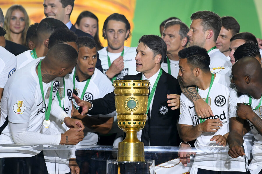 DFB-Pokal: Eintracht Frankfurt feiert Sensation - Trainer Niko Kovac (M) von Eintracht Frankfurt und seine Spieler jubeln über dem Sieg hinter dem Pokal bei der Siegerehrung auf dem Podium.