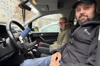 Diabetes, Muskelschwund, Erbkrankheit: Frankenberger Patient bleibt nach Fahrzeugumbau automobil - Sebastian und Manuela Hennen im umgebauten Familienauto: Links ist mit dem blauen Griff der nachgerüstete Knauf zu sehen, der das Lenken erleichtert.
