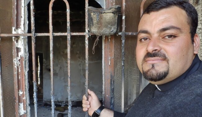 Die bedrohte Heimat der Christen - Priester Madschid vor seinem Haus: Die Terrormiliz IS hat mehr als die Hälfte der Gebäude in der Christen-Hochburg Karakosch zerstört.
