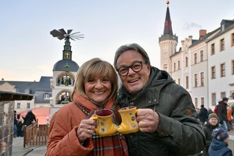 Die „Freie Presse“ testet Weihnachtsmärkte im Landkreis Zwickau: Wie schneidet Kirchberg ab? - Prominente Besucher beim Bummel auf dem Kirchberger Weihnachtsmarkt: Gitte und Klaus Röder stoßen mit den neuen gelben Glühweintassen auf die Adventszeit an.