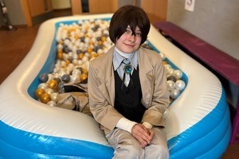 Die Lust, dem Alltag zu entfliehen: Cosplay-Treffen steigt in Reichenbach - Meli aus Mylau im beigen Mantel, mit hellgrauer Hose, schwarzer Weste, großem blauen Amulett, bandagierten Unterarmen und überm Nasenansatz gekreuzten dunklen Haaren als Detektiv Osamu Dazai aus der Manga-Serie „Bungo Stray Dogs“.