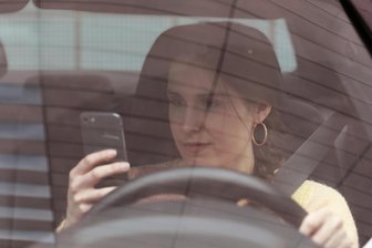 Die neue Liste der „Todsünden“ im Straßenverkehr - Eine Hand am Smartphone, die andere am Lenkrad des Fahrzeuges (gestelltes Foto): Diese schlechte Gewohnheit soll Autofahrern ausgetrieben werden.