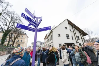 Die „Ochsentour“: Mit dem Bus entlang des Kulturhauptstadt-Projekts Purple Path - Jetzt gibt es - wie hier in Hainichen - auch Wegweiser zu Purple-Path-Kunstwerken, die am Eröffnungswochenende von Teilnehmern einer Bustour interessiert begutachtet wurden.