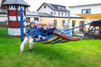 Die rote Rutsche ist kein Geheimnis mehr – was Mädchen und Jungen eines Burgstädter Kindergartens auf ihrem neuen Spielplatz erwartet - Die Hängemattenschaukel hat Anna Lenas (2. v. r.) Vater aufgebaut. Gemeinsam mit ihren Kindergartenfreunden durfte die Fünfjährige das neue Spielgerät schon testen.
