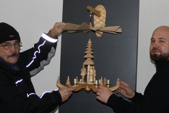 Die Zeit der Pyramiden beginnt mit Verspätung - Peter Laube (links) und Christian Landrock platzieren eine traditionelle Hängepyramide mit drei Figuren und einem geschnitzten Baum als Achse in der Mitte in der Ausstellung. 
