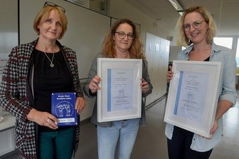 Diesterweg-Grundschüler aus Auerbach lösen ihre Konflikte künftig selbst - Regine Heinig (links) vom Verein Regenbogenbus mit der Plakette zur Zertifizierung der Diesterweg-Grundschule sowie Schulleiterin Anett Josiger (Mitte) und Hortleiterin Juliane Müller.