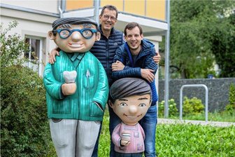 Diskussion um Vater- und-Sohn-Maskottchen in Plauen: Wie viel Veränderung darf sein? - Vater und Sohn bei Vater und Sohn: Utz und Tobias Damm freuen sich über das neuste Figurenpaar der Reihe. Mit Zahnprothese und Gebiss weisen sie seit Mitte August auf die Praxis von Dr. Utz Damm hin. 