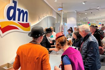 DM in Chemnitzer Innenstadt nach Umbau wieder auf: Spendenaktion für Fritz-Theater - Hardy Hoosman saß als Karl Valentin an der Kasse. Isabelle Weh (links) und Alica Weirauch in ihren Rollen als Pepeto und Immobile halfen beim Einpacken.