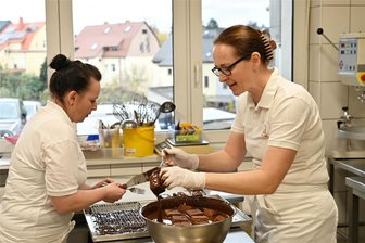 Dominosteine in Handarbeit: Peniger Bäckerei nimmt Herausforderung an - In der Peniger Bäckerei & Konditorei Sparschuh-Helbig entstehen Dominosteine in Handarbeit: Mitarbeiterin Nicole Boehm (links) und Peggy Sparschuh überziehen die Dominosteine mit Kuvertüre.