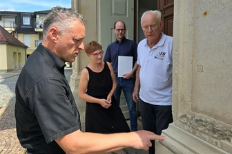 Doppelter Grund zur Freude in Werdau: Neue Pfarrerin und Geld für die Marienkirche - Der Putz am Sandsteinportal des Haupteingangs der Marienkirche bröckelt: Für die Sanierung hat Landrat Carsten Michaelis am Donnerstag an die Mitglieder des Kirchenvorstands, Birgit Justel, Hartmut Baumgartl und Wolfgang Dietrich (v. l.), einen symbolischen Zuwendungsbescheid vorbeigebracht.
