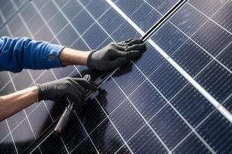 Dorf im Erzgebirge baut Solaranlagen aufs Dach seiner Feuerwehrdepots - Ein Handwerker montiert Photovoltaikmodule auf einem Dach. Solche Anlagen sind für die Feuerwehrdepots in Zschorlau und Burkhardtsgrün geplant.