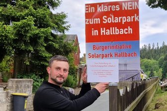 Dorf im Erzgebirge zu Votum um Solarpark aufgerufen - Michael Ruscher befestigt Info-Zettel zum Votum an den Plakaten der Bürgerinitiative.