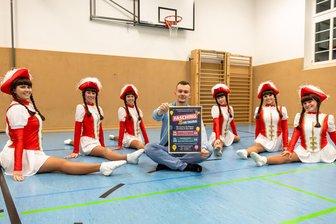 Dorfparty & Fasching-Premiere in Taura: Drei Tage Party und Karneval in der Mehrzweckhalle - Beweglichkeitsvergleich auf Augenhöhe: Während die Tänzerinnen der Funkengarde mühelos im Spagat sitzen, begnügt sich Veranstalter Pascal Köhler in ihrer Mitte mit dem Schneidersitz.