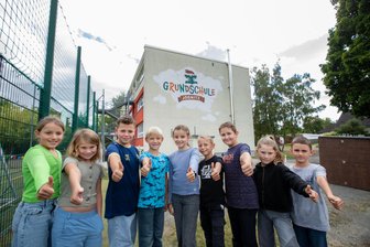 Drei auf einen Schlag: Jößnitz feiert großes Jubiläen-Wochenende - Schüler der Klasse 3a vor dem Logo der Grundschule, das erst kürzlich angebracht wurde.