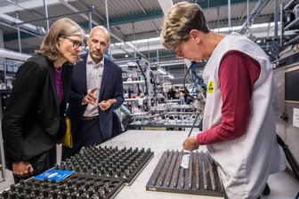 Drei Firmen fusionieren im Erzgebirge zu Großbetrieb – IG-Metall-Chefin äußert Sorge um Osten - Die IG-Metall-Bundesvorsitzende Christiane Benner, mit Pulsotronic-Prokurist Raoul Scheidhauer, schaute Mitarbeiterin Kathleen Sonntag beim Verguss von Sensoren zu.