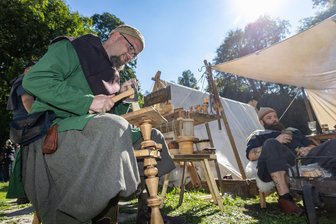 Drei Tage Auszeit vom modernen Leben: Was das Wikingerspektakel auf Burg Rabenstein in Chemnitz bietet - Michael Hübler schnitzt mit einer Behauaxt einen Löffel aus einem Stück Kiefernholz.