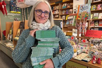 Druckfrisch: Hunderte Oelsnitzer Stadtpläne im Mülleimer gefunden - Jana May in der Buchhandlung am Markt mit nagelneuen Stadtplänen, die aus dem Papiermüll gerettet wurden.