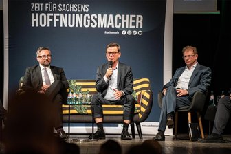 E-Auto-Krise bei Volkswagen: Weshalb VW-Sachsen-Manager Edig um Geduld bittet - Auf dem „Sachsensofa“ diskutierten im Crimmitschauer Theater: Wirtschaftsminister Martin Dulig (li.) und VW-Sachsen-Manager Thomas Edig. Rechts daneben und ebenfalls mit von der Partie: Crimmitschaus OB André Raphael.