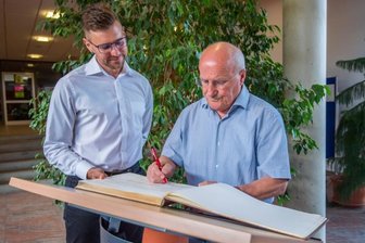 Ehrung für einen Bewahrer der Neukirchener Ortsgeschichte - Dietmar Sommerfeld trägt sich im Beisein von Bürgermeister Sascha Thamm (links) in der Oberschule des Ortes ins Goldene Buch der Gemeinde Neukirchen ein. Damit wird er für sein langjähriges ehrenamtliches Engagement geehrt. 